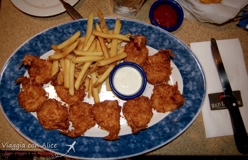 Piatto di gamberoni ricoperti con panatura al cocco serviti con salsa di avocado e patatine fritte